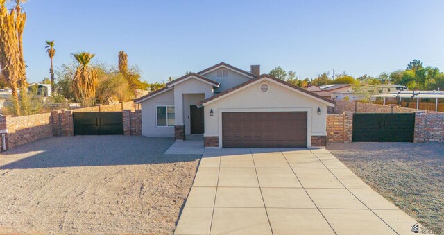 view of front of house featuring stucco siding, concrete driveway, fence, and a gate