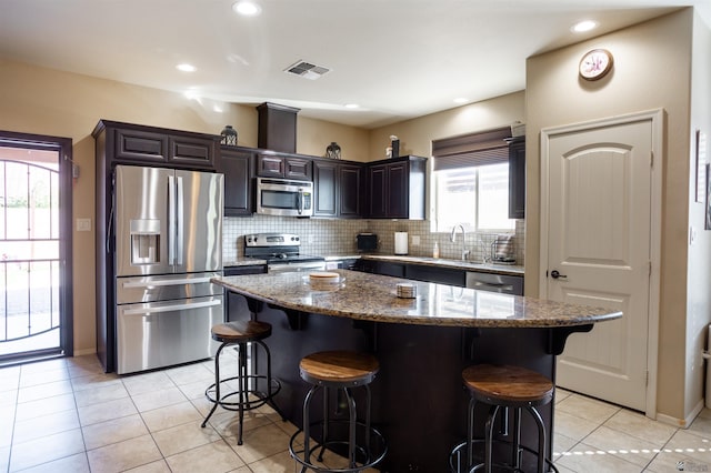 kitchen with visible vents, backsplash, stainless steel appliances, and a kitchen bar