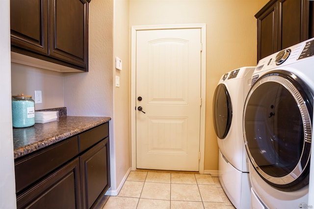 washroom featuring washer and dryer, baseboards, cabinet space, and light tile patterned floors