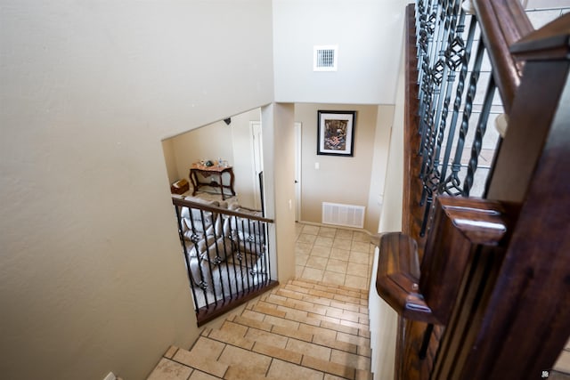 entryway with light tile patterned flooring, visible vents, and a towering ceiling