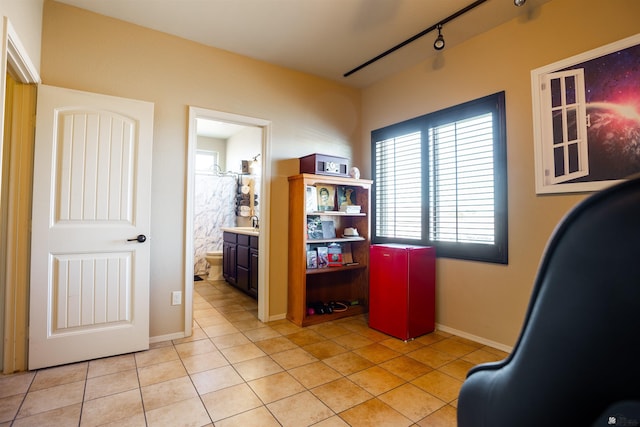 office area with track lighting, light tile patterned floors, baseboards, and a sink