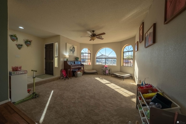 rec room featuring a textured ceiling, carpet floors, and ceiling fan