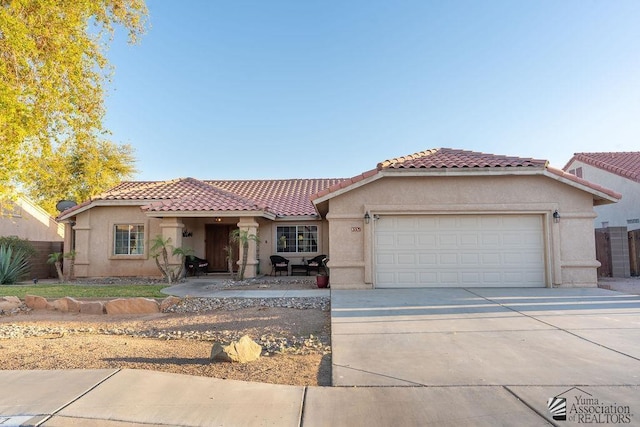 mediterranean / spanish home featuring fence, a tiled roof, stucco siding, driveway, and an attached garage