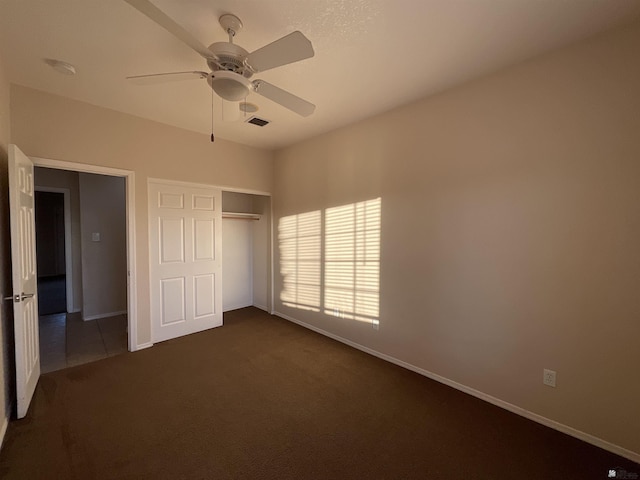 unfurnished bedroom featuring dark carpet, ceiling fan, and a closet