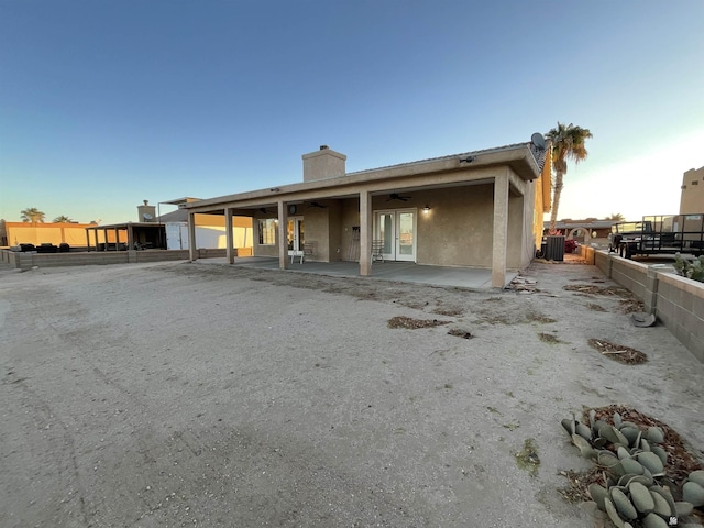 back house at dusk with ceiling fan and a patio area