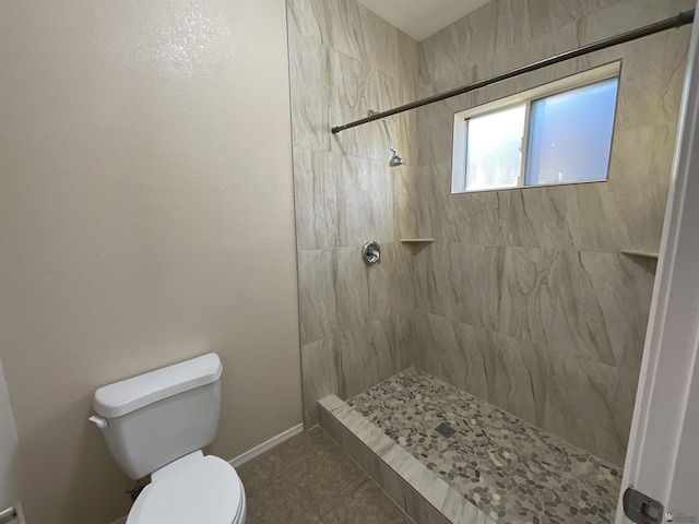 bathroom with toilet, a tile shower, and tile patterned floors