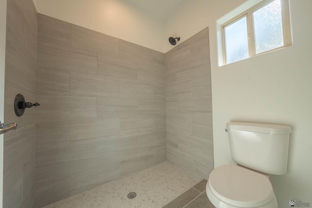 bathroom featuring tile patterned floors, toilet, and a tile shower