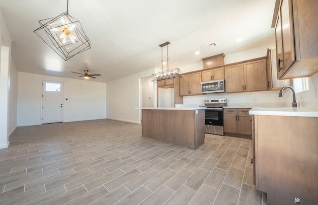 kitchen featuring a center island, sink, ceiling fan, decorative light fixtures, and stainless steel appliances