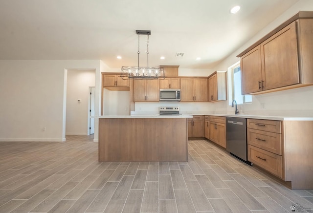 kitchen featuring pendant lighting, sink, light hardwood / wood-style flooring, appliances with stainless steel finishes, and a kitchen island