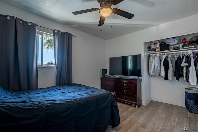 bedroom featuring ceiling fan, light hardwood / wood-style floors, a textured ceiling, and a closet