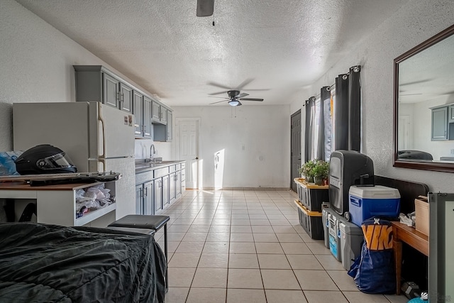 kitchen featuring ceiling fan, sink, white refrigerator, a textured ceiling, and light tile patterned floors