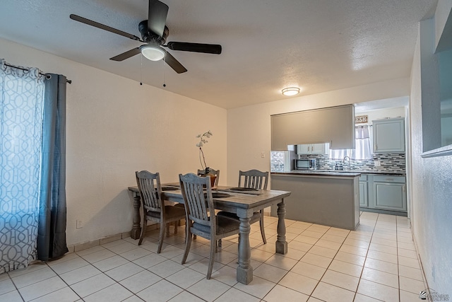 dining area featuring light tile patterned floors, ceiling fan, and sink