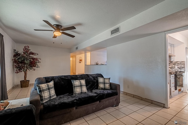 living room with ceiling fan, light tile patterned floors, and a textured ceiling