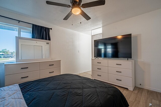 bedroom featuring a textured ceiling, light wood-type flooring, and ceiling fan