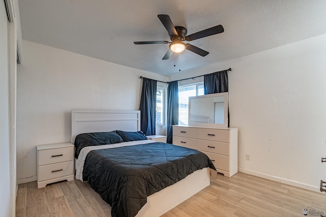 bedroom with a textured ceiling, light hardwood / wood-style flooring, and ceiling fan