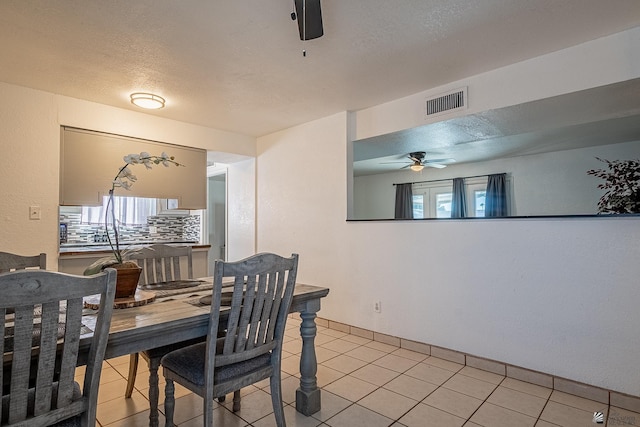 dining area featuring ceiling fan, light tile patterned flooring, and a textured ceiling