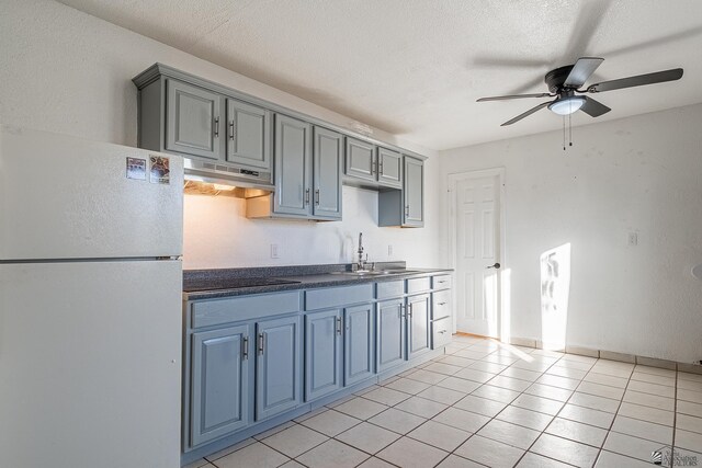 kitchen with cooktop, ceiling fan, sink, light tile patterned floors, and white refrigerator