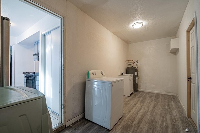 laundry room with hardwood / wood-style floors, a textured ceiling, washer / clothes dryer, and electric water heater