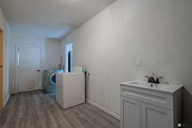 washroom featuring a textured ceiling, dark hardwood / wood-style floors, washer and clothes dryer, and sink