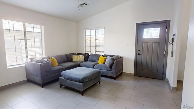 living room featuring light tile patterned flooring, visible vents, baseboards, and vaulted ceiling