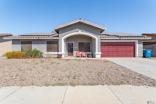 ranch-style house featuring stucco siding, a tile roof, roof mounted solar panels, concrete driveway, and an attached garage