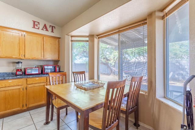 dining room featuring light tile patterned floors, lofted ceiling, and a toaster