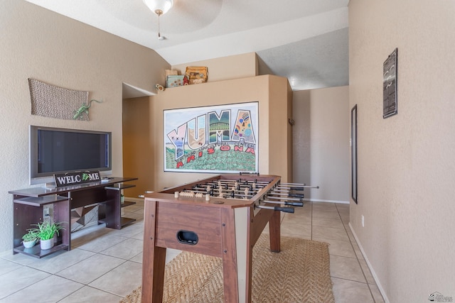 recreation room featuring ceiling fan, baseboards, light tile patterned flooring, and vaulted ceiling