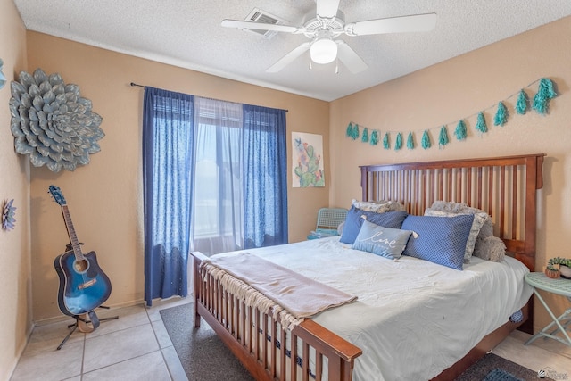 bedroom with light tile patterned flooring, visible vents, a textured ceiling, and ceiling fan