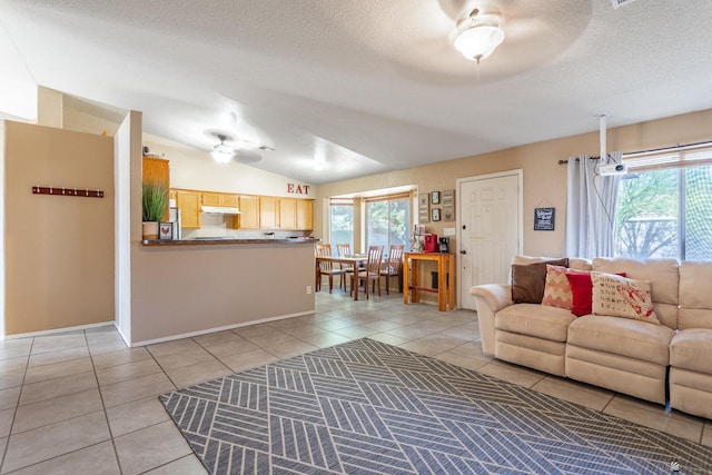 living area featuring light tile patterned floors, a healthy amount of sunlight, ceiling fan, and vaulted ceiling