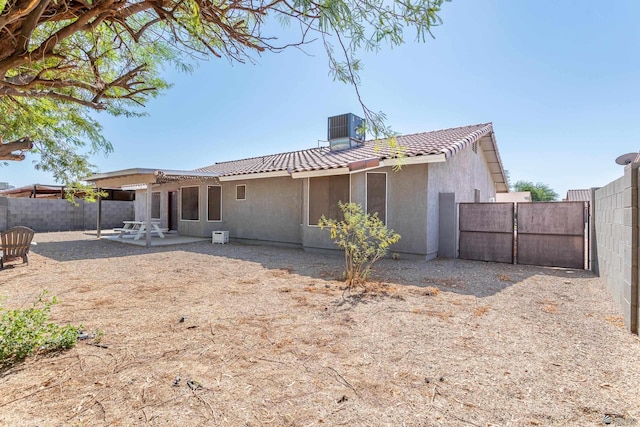 rear view of house with fence, a tiled roof, central AC, stucco siding, and a patio area