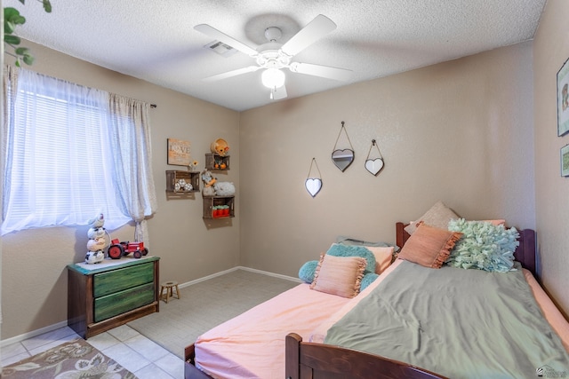 bedroom featuring visible vents, a ceiling fan, a textured ceiling, light tile patterned floors, and baseboards