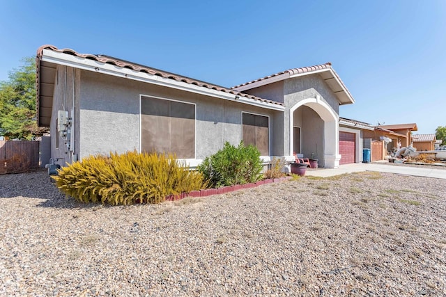 view of front facade featuring stucco siding, a tiled roof, concrete driveway, and a garage