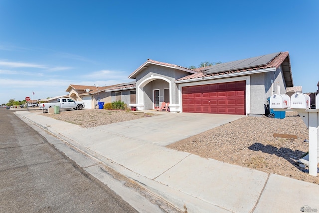 view of front of house with stucco siding, roof mounted solar panels, concrete driveway, an attached garage, and a tiled roof