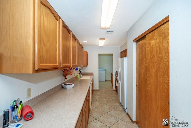 kitchen featuring washer / dryer, white fridge, light tile patterned floors, and sink