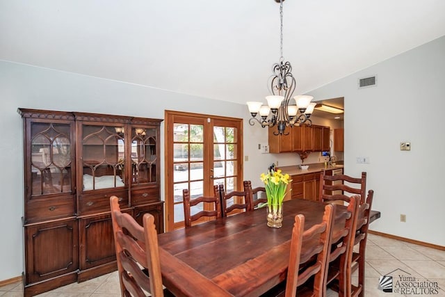 dining room featuring french doors, light tile patterned floors, a chandelier, and vaulted ceiling