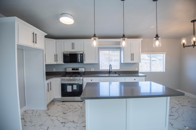 kitchen with a center island, hanging light fixtures, white cabinets, appliances with stainless steel finishes, and sink