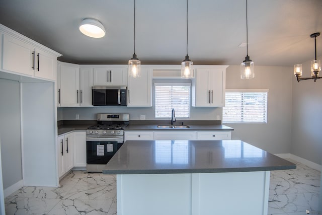 kitchen featuring sink, white cabinets, hanging light fixtures, a kitchen island, and appliances with stainless steel finishes