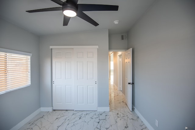 unfurnished bedroom with ceiling fan and a closet