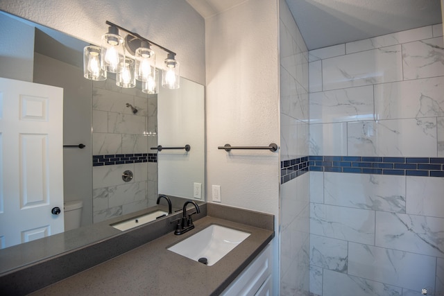 bathroom featuring a tile shower, vanity, and toilet