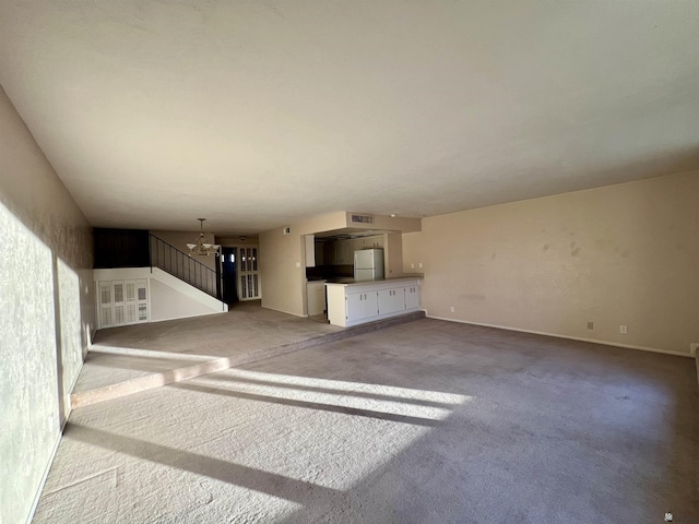 unfurnished living room with carpet flooring and a notable chandelier