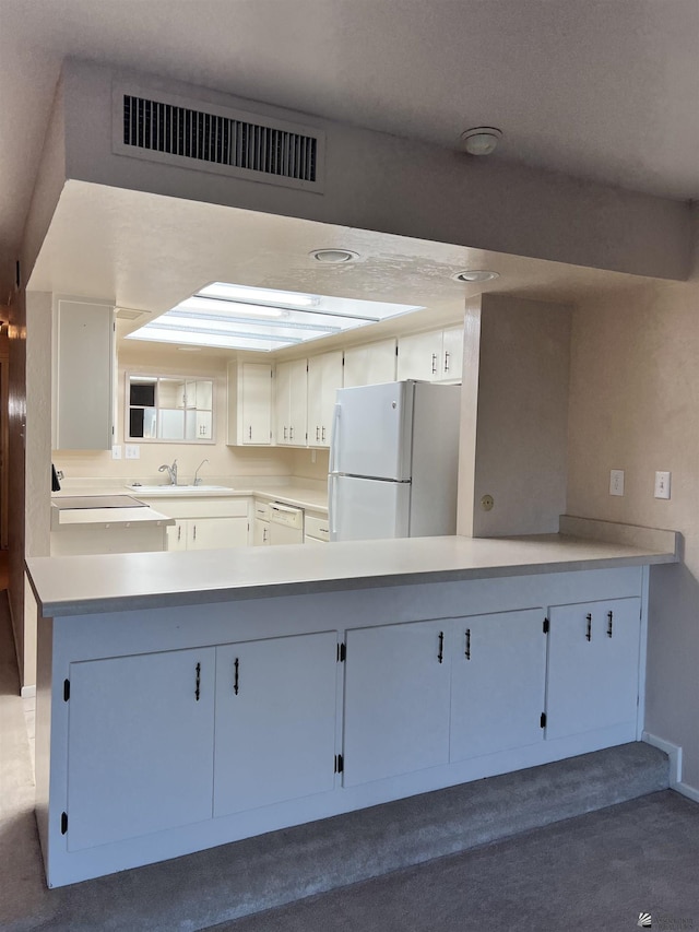 kitchen featuring kitchen peninsula, white cabinetry, white appliances, and sink