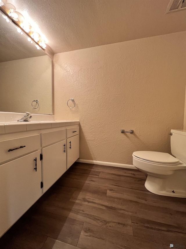 bathroom with toilet, vanity, a textured ceiling, and hardwood / wood-style flooring