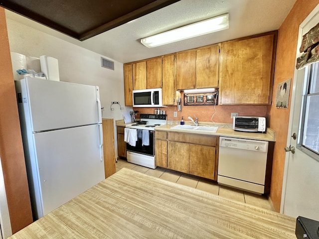 kitchen featuring sink, light tile patterned floors, and white appliances