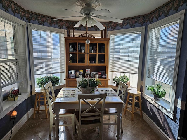 tiled dining space with ceiling fan and a textured ceiling