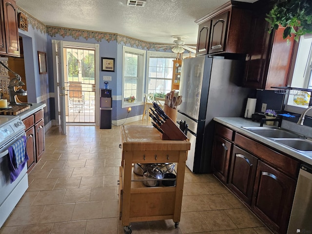 kitchen with a textured ceiling, light tile patterned floors, stainless steel appliances, and sink