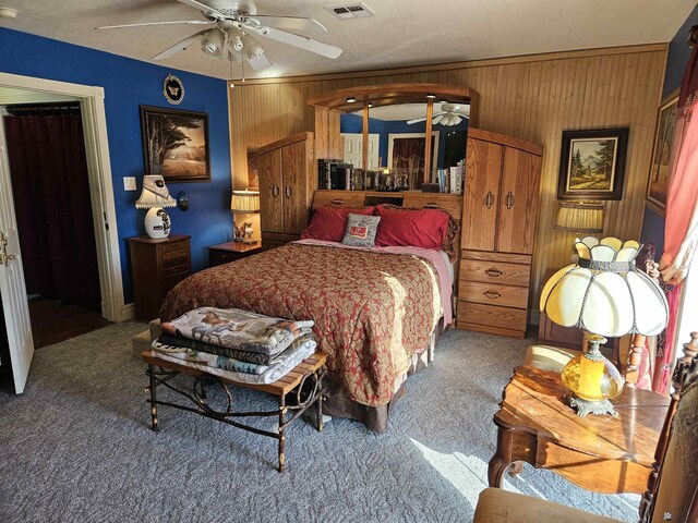 bedroom with ceiling fan, a textured ceiling, wood walls, and carpet flooring