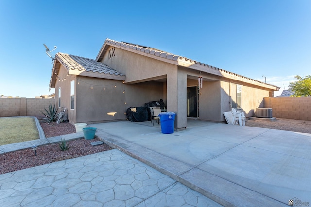 back of property with central air condition unit and a patio