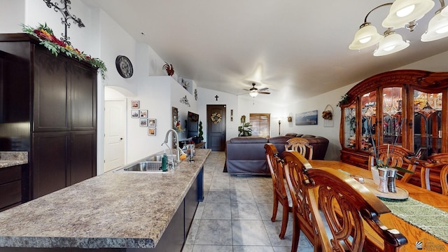 dining space with vaulted ceiling, light tile patterned floors, ceiling fan with notable chandelier, and sink