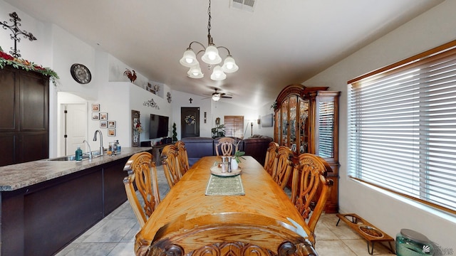 tiled dining room featuring vaulted ceiling, ceiling fan with notable chandelier, and sink