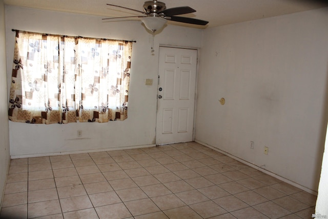 spare room with ceiling fan and light tile patterned flooring